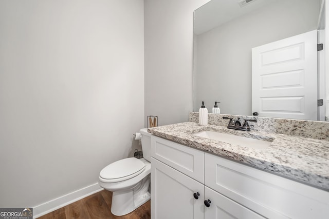 bathroom with wood finished floors, vanity, toilet, and baseboards