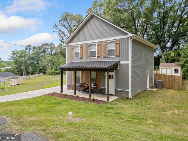 view of front facade with central AC unit, stone siding, concrete driveway, a patio area, and board and batten siding