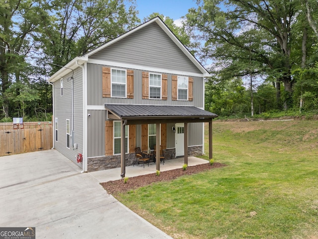 view of front of property featuring a front yard, a patio, stone siding, and board and batten siding
