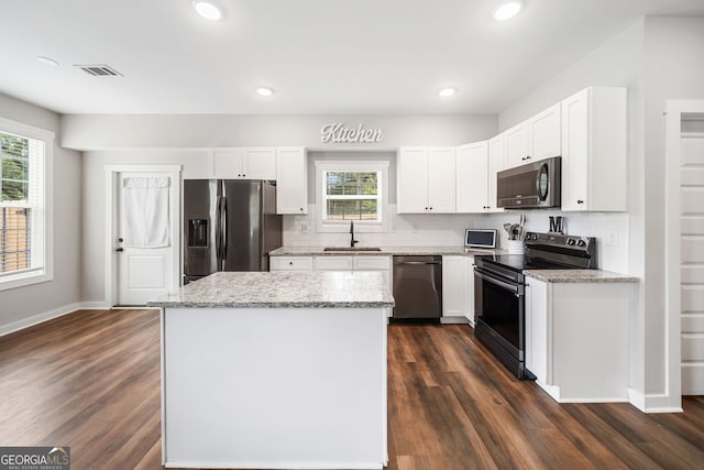 kitchen with appliances with stainless steel finishes, healthy amount of natural light, a kitchen island, dark wood-type flooring, and recessed lighting