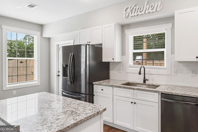 kitchen featuring stainless steel appliances, a sink, white cabinetry, and backsplash