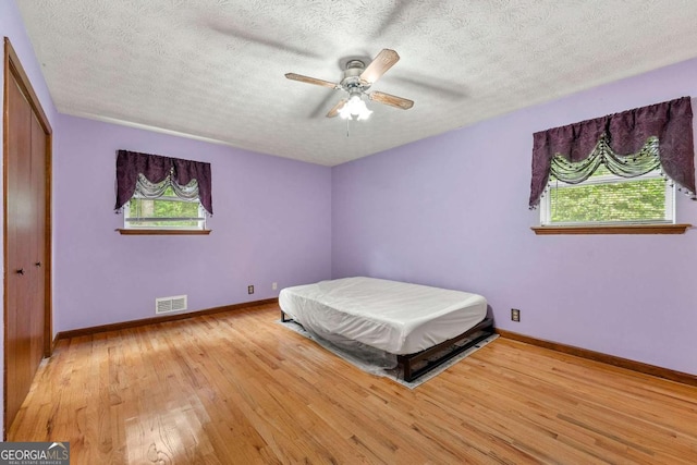 57 Fair Oaks Dr SE, Conyers, GA 30094 - bedroom featuring wood finished floors, a textured ceiling, baseboards, a ceiling fan, and a closet
