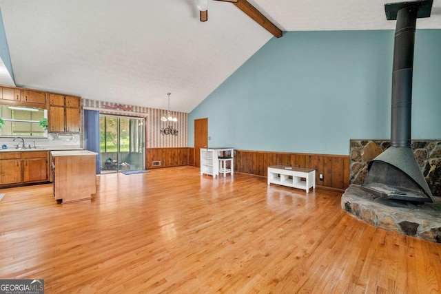 57 Fair Oaks Dr SE, Conyers, GA 30094 - living room with a wood stove, light wood-type flooring, a wainscoted wall, a chandelier, and wooden walls