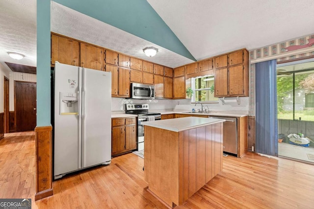 57 Fair Oaks Dr SE, Conyers, GA 30094 - kitchen with stainless steel appliances, light wood-style floors, light countertops, brown cabinets, and vaulted ceiling