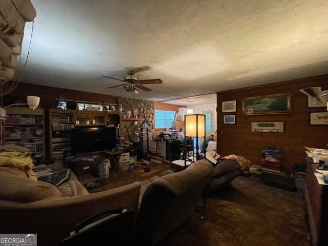 living room with a ceiling fan and wooden walls