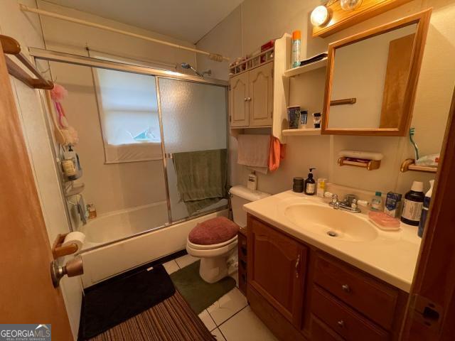 full bath with toilet, vanity, bath / shower combo with glass door, and tile patterned flooring