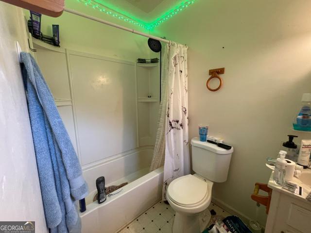 full bathroom with toilet, tile patterned floors, shower / bath combination with curtain, and baseboards