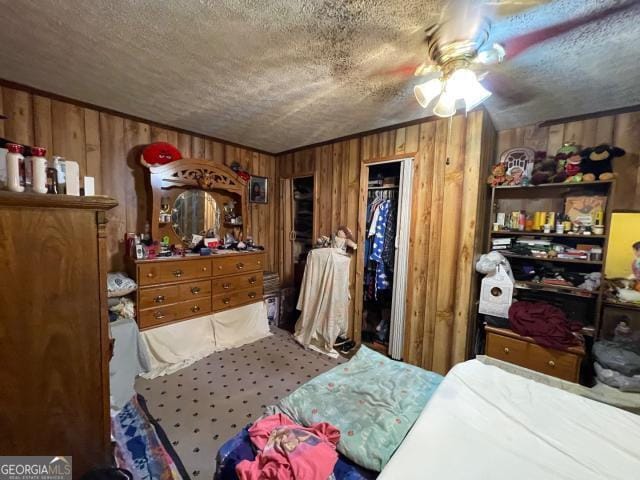 bedroom featuring a textured ceiling, wooden walls, carpet, and a ceiling fan