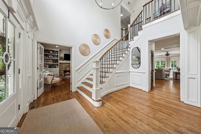 2195 Hickory Hill Rd, Alpharetta, GA 30004 - foyer entrance with stairway, a decorative wall, light wood-style flooring, a fireplace, and a high ceiling