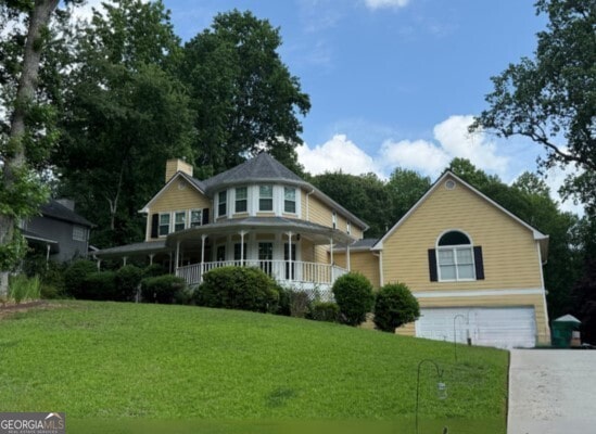 1713 Dudley Dr, Woodstock, GA 30188 - victorian house featuring a garage, covered porch, a front yard, driveway, and a chimney