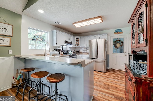 206 Middle Creek Rd, Springfield, GA 31329 - kitchen with stainless steel appliances, a peninsula, a breakfast bar area, light wood-style floors, and white cabinets