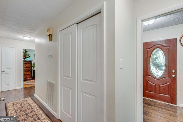 entrance foyer with wood finished floors, a textured ceiling, and baseboards