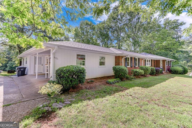 single story home featuring a front lawn, an attached carport, and driveway