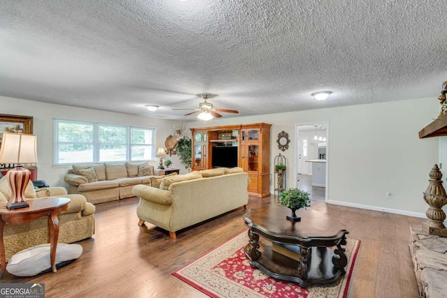 living area featuring wood finished floors, a textured ceiling, and ceiling fan