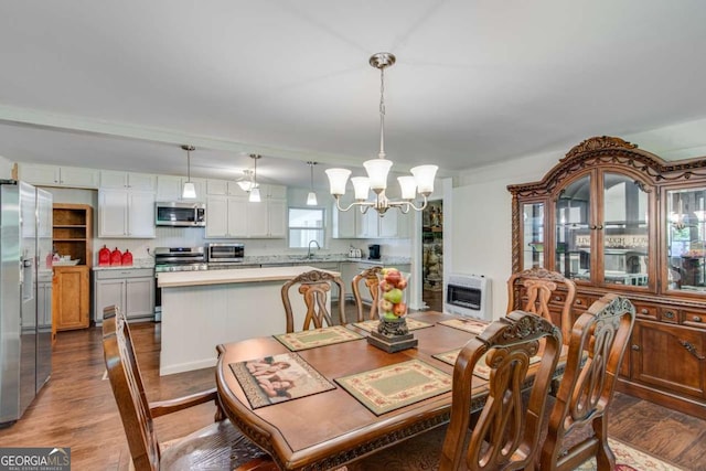dining area featuring heating unit, a chandelier, and wood finished floors