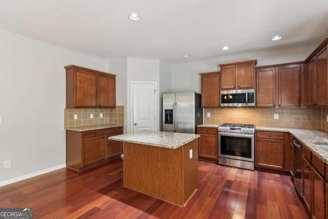 5655 Stevehaven Ln, Cumming, GA 30028 - kitchen with stainless steel appliances, dark wood-type flooring, tasteful backsplash, a center island, and light stone countertops