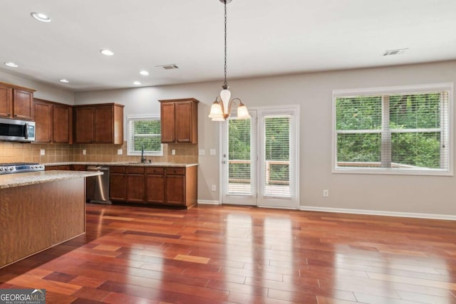 5655 Stevehaven Ln, Cumming, GA 30028 - kitchen featuring stainless steel appliances, a sink, a chandelier, decorative backsplash, and dark wood-style flooring