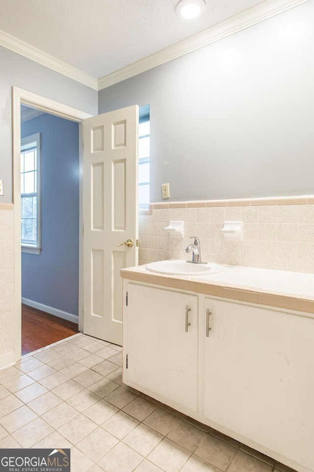 1878 Blalock Ave, Waycross, GA 31503 - bathroom featuring a sink, tile patterned floors, crown molding, tile walls, and a wainscoted wall