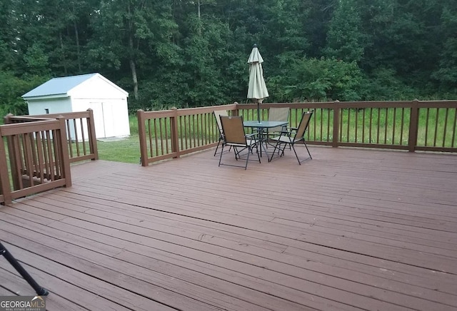 1495 Martin Mill Rd, Newnan, GA 30263 - wooden deck with outdoor dining space, an outbuilding, a storage unit, a yard, and a wooded view