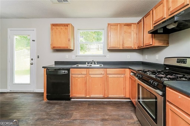 kitchen with stainless steel gas range, dishwasher, under cabinet range hood, a sink, and dark countertops