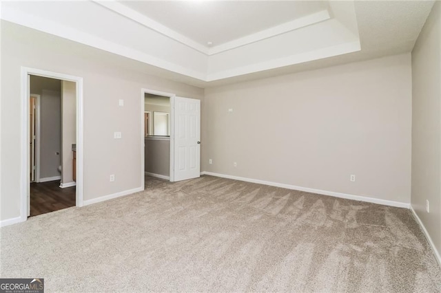 unfurnished bedroom featuring carpet flooring, a raised ceiling, and baseboards