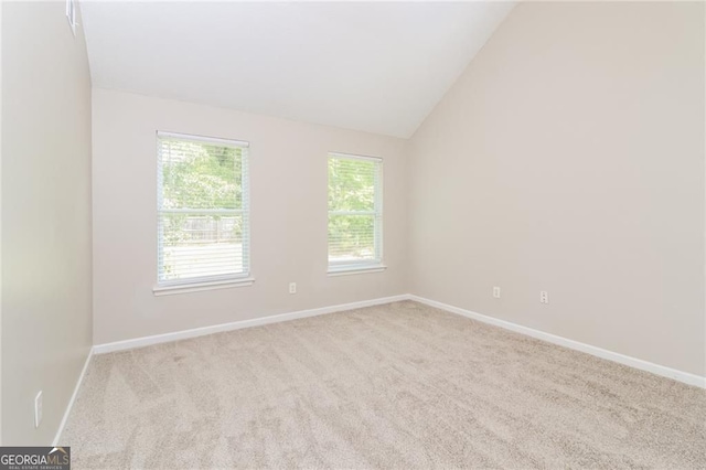 empty room featuring carpet flooring, baseboards, and lofted ceiling