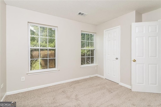 unfurnished bedroom with carpet, multiple windows, baseboards, and a textured ceiling
