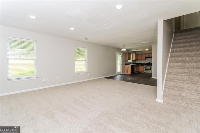unfurnished living room with dark colored carpet, baseboards, stairway, and recessed lighting