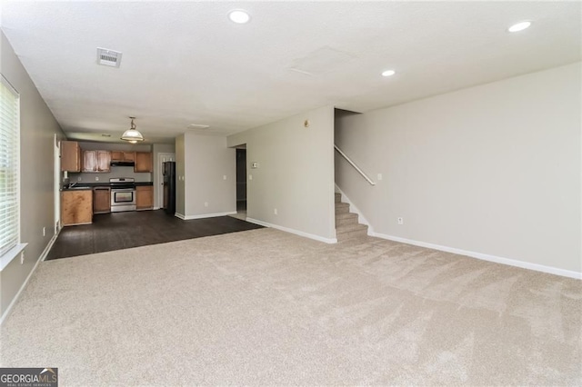unfurnished living room with dark colored carpet, stairs, baseboards, and recessed lighting
