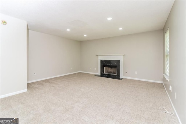 unfurnished living room with carpet, recessed lighting, a high end fireplace, and baseboards
