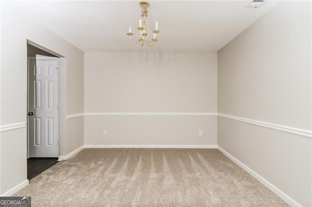spare room featuring carpet, a chandelier, and baseboards