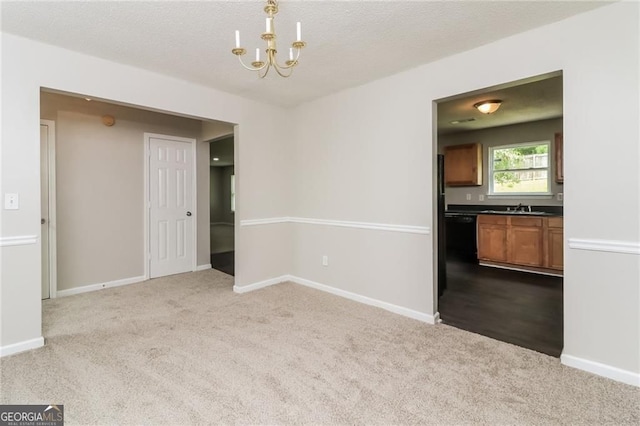 unfurnished dining area with dark carpet, a chandelier, a sink, and baseboards