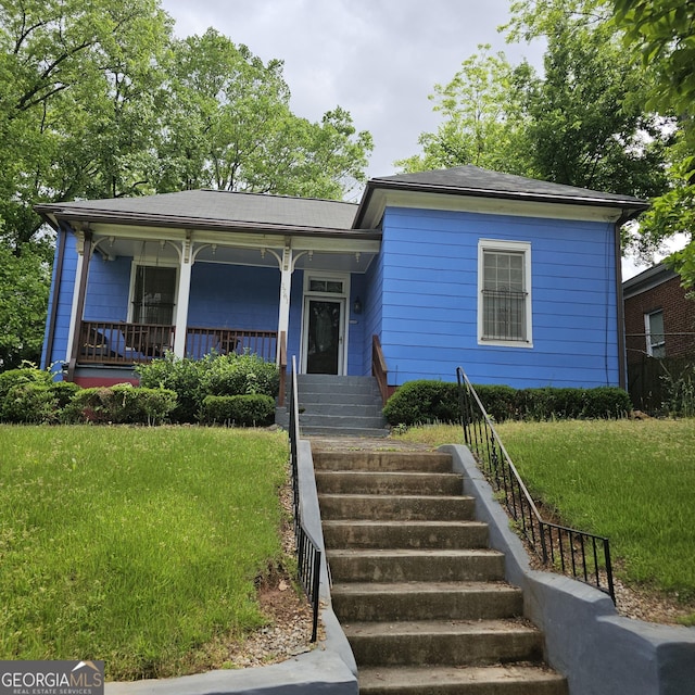 view of front of house with a front yard, covered porch, and stairs