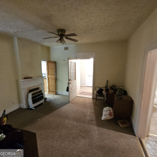 living area featuring ceiling fan, carpet, a textured ceiling, a fireplace, and heating unit