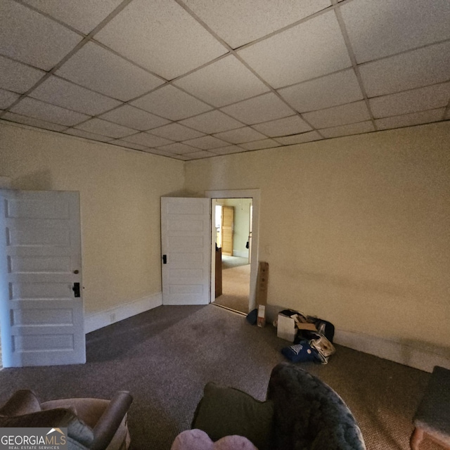 carpeted living room with a drop ceiling and baseboards