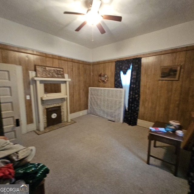 carpeted living room featuring wooden walls and ceiling fan