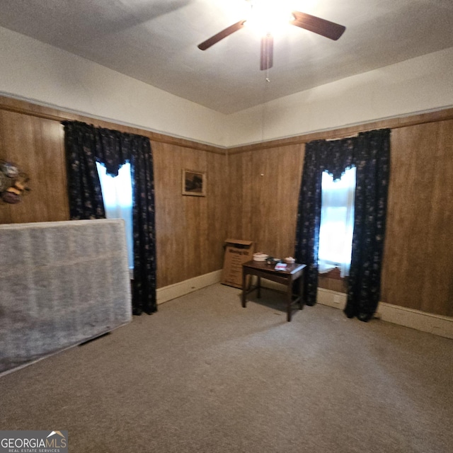 bedroom with multiple windows, wood walls, light carpet, and ceiling fan