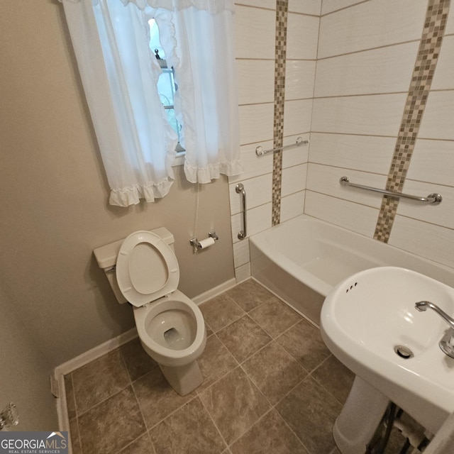 bathroom with toilet, baseboards, a sink, and tile patterned flooring