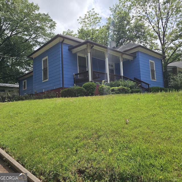 view of front of house with a chimney, a front yard, and a porch