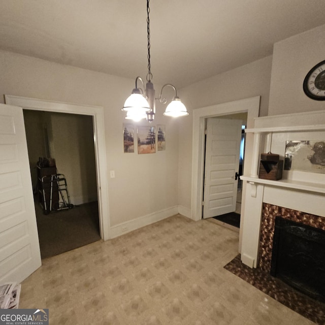 unfurnished dining area featuring a chandelier, a tiled fireplace, and baseboards