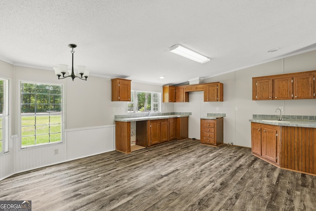 kitchen with brown cabinets, vaulted ceiling, dark wood-style floors, a chandelier, and a sink