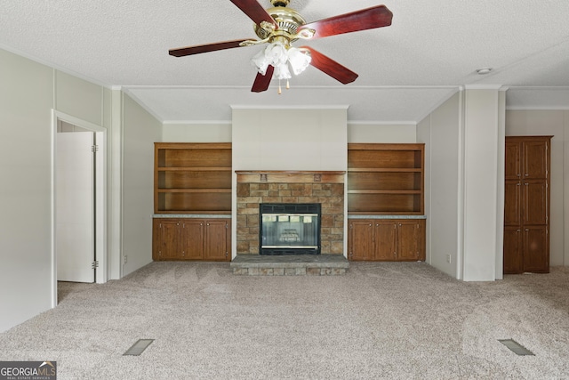 unfurnished living room with ornamental molding, carpet, a textured ceiling, a fireplace, and a ceiling fan