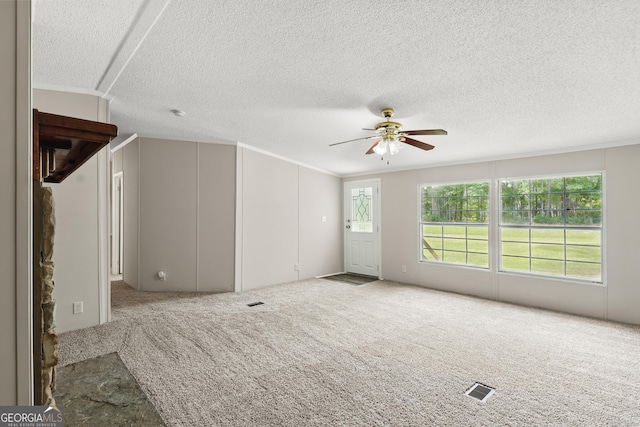 unfurnished living room with ceiling fan, carpet, a textured ceiling, and crown molding