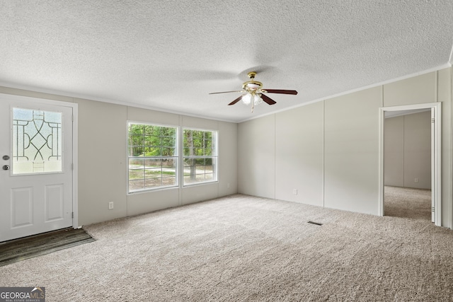 carpeted entrance foyer featuring a ceiling fan, crown molding, and a textured ceiling