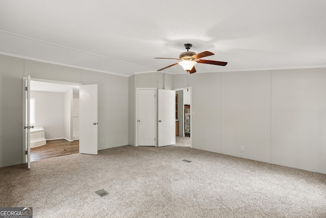 unfurnished bedroom with carpet floors, ornamental molding, a ceiling fan, and two closets