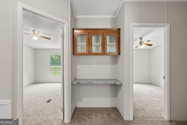 hallway with carpet, a textured ceiling, and ornamental molding