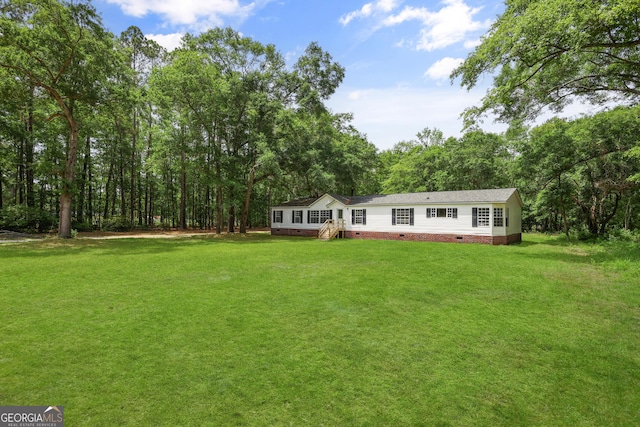 view of grassy yard featuring a wooded view