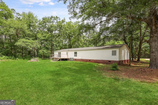 rear view of property featuring crawl space, a yard, central AC, and view of scattered trees