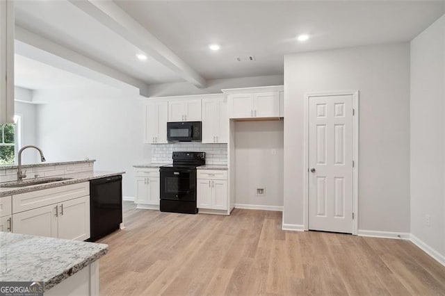 kitchen featuring black appliances, a sink, white cabinets, tasteful backsplash, and light wood-style flooring