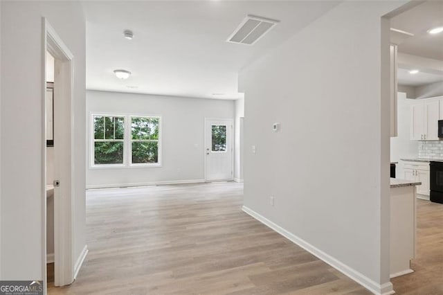 hallway with light wood-type flooring, baseboards, and recessed lighting